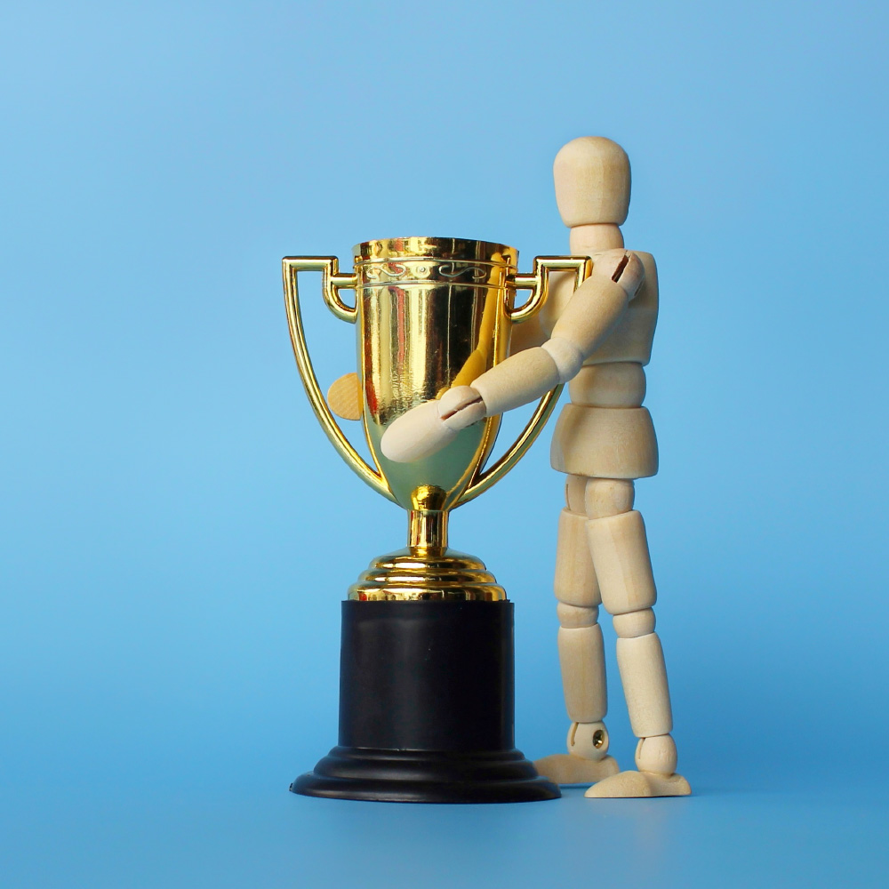 wooden figure hugging a trophy